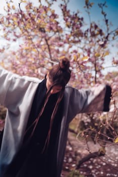 Beautiful dramatic young woman wearing kimono with cherry blossoms, sakura view. High quality photo