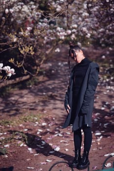 Beautiful dramatic young woman wearing black with cherry blossoms, sakura view. High quality photo