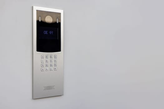 Doorbell with video camera and microphone, on the white wall of an apartment building, doorbell camera.