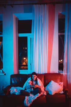 Beautiful young girl watching movie at home in a dark room with a popcorn bucket and playing with her dog and sits in front of a monitor or TV watching movie. Crazy emotions. High quality photo