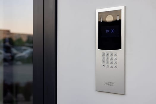 Doorbell with video camera and microphone, on the white wall of an apartment building, doorbell camera.