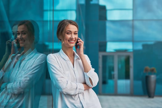 Businesswoman successful woman business person standing outdoor corporate building exterior cell phone Pensive elegance cute caucasian professional businesswoman