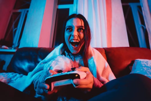 Close up portrait of A gamer or a streamer girl at home in a dark room with a game controller playing with her dog and sits in front of a monitor or TV. High quality photo