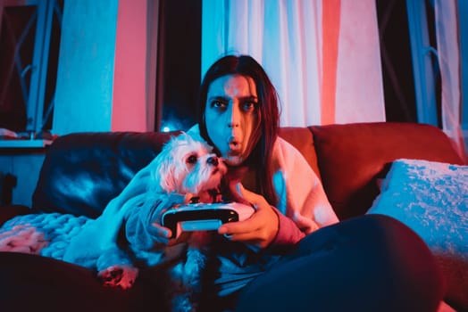 Close up portrait of A gamer or a streamer girl at home in a dark room with a game controller playing with her dog and sits in front of a monitor or TV. Crazy emotions. High quality photo