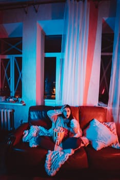 Beautiful young girl watching movie at home in a dark room with a popcorn bucket playing with her dog and sits in front of a monitor or TV watching movie. Crazy emotions. High quality photo