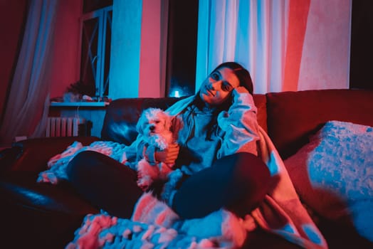 Close up portrait of A gamer or a streamer girl at home in a dark room with a game controller playing with her dog and sits in front of a monitor or TV. High quality photo