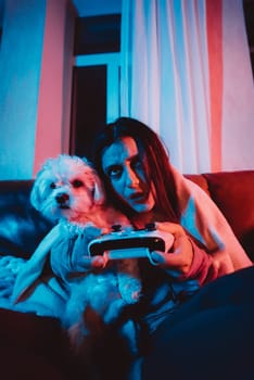 Close up portrait of A gamer or a streamer girl at home in a dark room with a game controller playing with her dog and sits in front of a monitor or TV. High quality photo