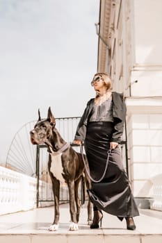 A woman walks with her Great Dane in an urban setting, enjoying the outdoors and the company of her dog