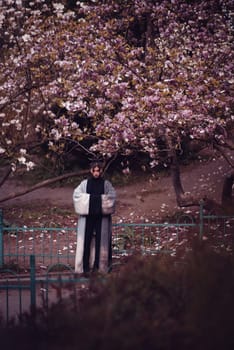 Beautiful dramatic young woman wearing kimono with cherry blossoms, sakura view. High quality photo