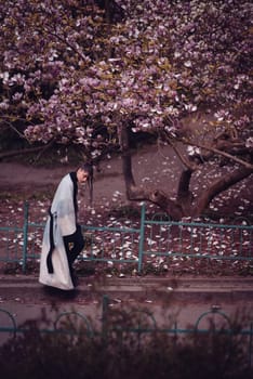 Beautiful dramatic young woman wearing kimono with cherry blossoms, sakura view. High quality photo