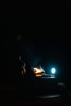 Man preparing bbq grill to cook on fire. Outside dark shot. Freeze moment of fire. High quality photo
