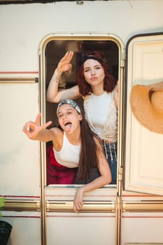 Happy hippie friends are having a good time together in a camper trailer. Holiday, vacation, trip concept. High quality photo