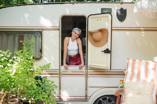 Happy hippie girl are having a good time in a camper trailer. Holiday, vacation, trip concept.High quality photo