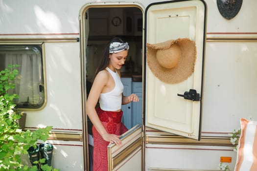 Happy hippie girl are having a good time in a camper trailer. Holiday, vacation, trip concept.High quality photo