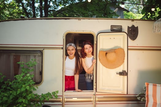 Happy hippie friends are having a good time together in a camper trailer. Holiday, vacation, trip concept. High quality photo