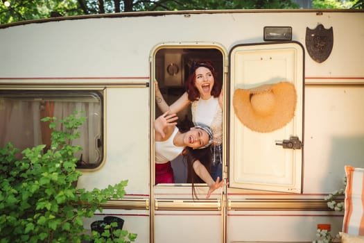 Happy hippie friends are having a good time together in a camper trailer. Holiday, vacation, trip concept. High quality photo