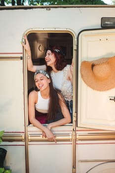 Happy hippie friends are having a good time together in a camper trailer. Holiday, vacation, trip concept. High quality photo