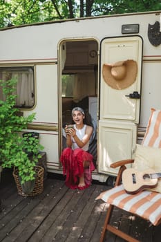 Happy hippie girl are having a good time with cup of tea in camper trailer. Holiday, vacation, trip concept.High quality photo