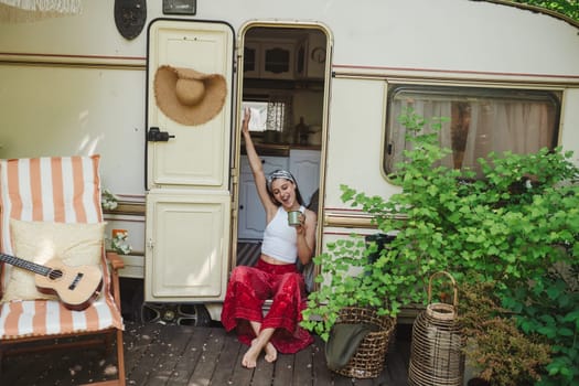 Happy hippie girl are having a good time with cup of tea in camper trailer. Holiday, vacation, trip concept.High quality photo