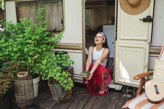 Happy hippie girl are having a good time with cup of tea in camper trailer. Holiday, vacation, trip concept.High quality photo