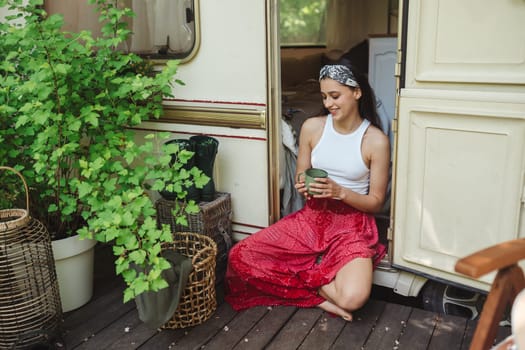 Happy hippie girl are having a good time with cup of tea in camper trailer. Holiday, vacation, trip concept.High quality photo