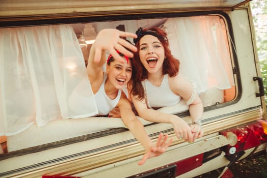 Happy hippie friends are having a good time together in a camper trailer. Holiday, vacation, trip concept. High quality photo