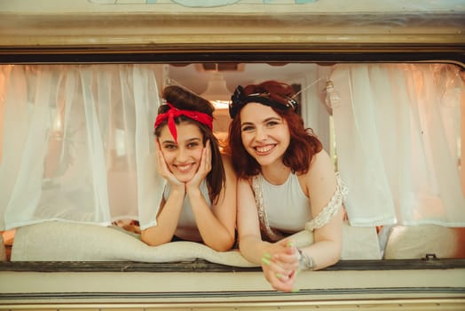 Happy hippie friends are having a good time together in a camper trailer. Holiday, vacation, trip concept. High quality photo