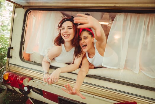 Happy hippie friends are having a good time together in a camper trailer. Holiday, vacation, trip concept. High quality photo