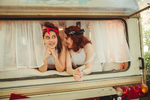 Happy hippie friends are having a good time together in a camper trailer. Holiday, vacation, trip concept. High quality photo