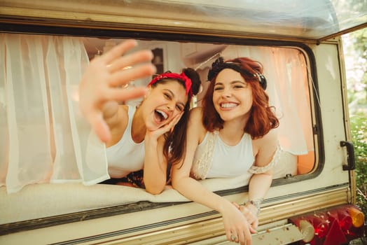 Happy hippie friends are having a good time together in a camper trailer. Holiday, vacation, trip concept. High quality photo