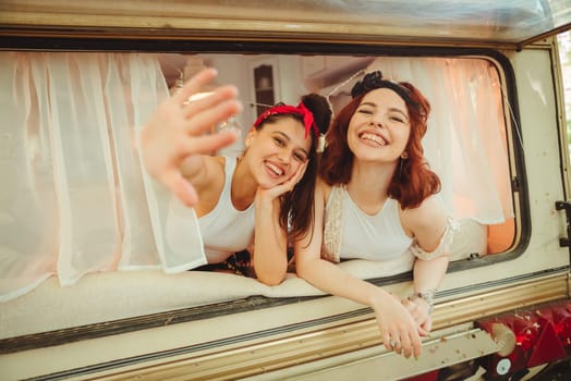 Happy hippie friends are having a good time together in a camper trailer. Holiday, vacation, trip concept. High quality photo