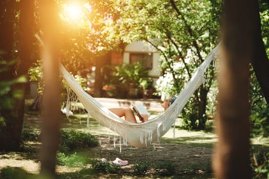 Happy hippie girl is reading a book in hammock having a good time with playing in camper trailer. Holiday, vacation, trip concept.High quality photo