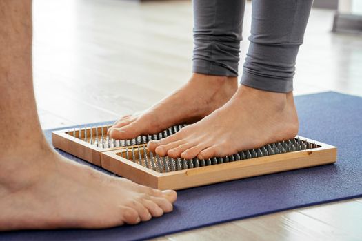 closeup of yoga person standing on a sadhu board with sharp nails