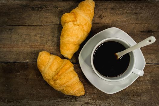 Breakfast with croissants and black coffee composition on wooden background. Flat lay