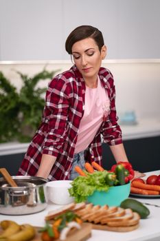 Housewife enjoying her new house and new kitchen while cooking or baking. Young woman cooking in the kitchen. Young woman on bright kitchen. New house concept. 