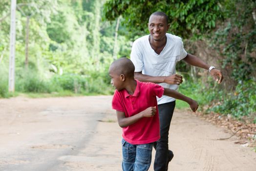 happy family, father and son having fun running outside on a forest road,...