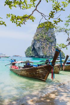MAYA BAY, THAILAND - APRIL 14, 2014: Dramatic karst geography stands tall above traditional Thai longtail boats docked in the popular Maya Bay.