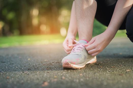 Woman tying her sport shoes in the park