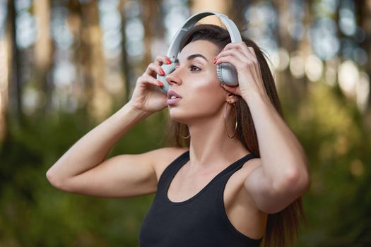 Young woman listening to music in the forest. Woman listening to music during workout.