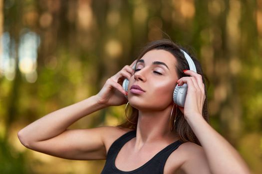 Young woman listening to music in the forest. Woman listening to music during workout.
