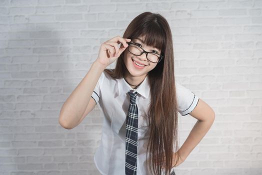 Portrait of cute student girl wearing japan uniform on gray background