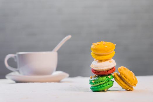 colourful french macaroons with cup of coffee on white background