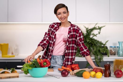 Happy of new home pretty housewife cutting ingredients on table cooking lunch standing in the kitchen with one hand on a side. Healthy lifestyle. Cooking at home for loving family. New house concept.