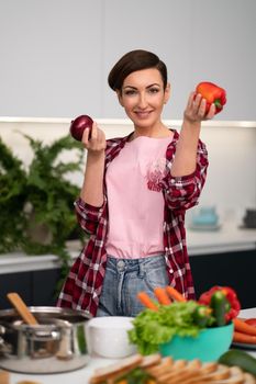 Holding apples in the hands housewife wearing plaid shirt with a short hairstyle while cooking apple pie standing at the kitchen. Healthy food at home.