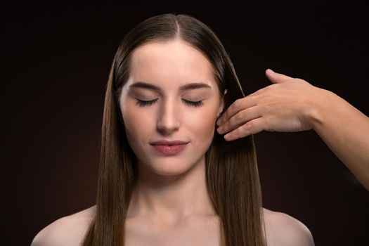 Hairstylist working on a fashion model beautiful face isolated on black background. Beautiful model at make up artist. Make-up artist, applying eye shadow to the model. 