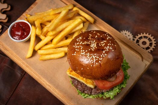 Top view. Beef burger are served with french fries on decorative wooden board with tomato sauce with wooden decorative pieces of simple mechanism. Restaurant, Fast food concept. Street food concept.