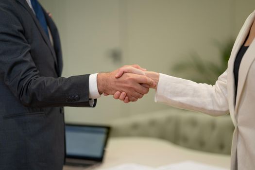 Female and male handshake. Young freelancers working together doing handshake at business meeting at the office. Two young business people standing in the office, shaking hands.