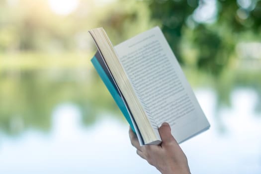 Woman is reading book in beautiful park and pond relax and peaceful environment background.