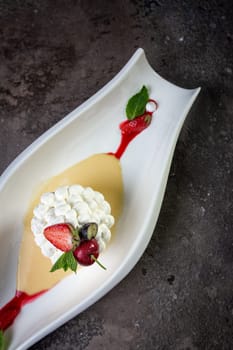 white dessert fresh meringue with strawberries on a beautiful white dish on a dark background.