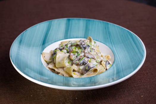 pasta with mushrooms and sauce in a blue plate.